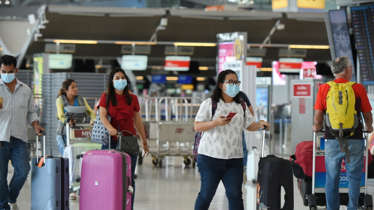Voyageur.euses portant des masques dans un aéroport.