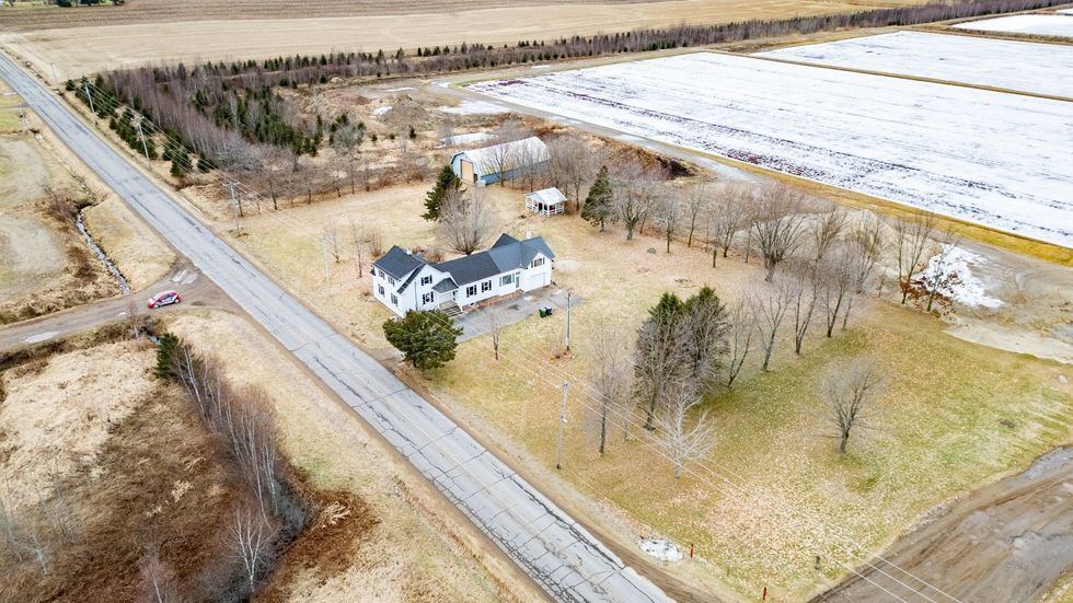 Vue a\u00e9rienne d'une grande maison blanche et grise \u00e0 vendre sur un terrain spacieux au Qu\u00e9bec.