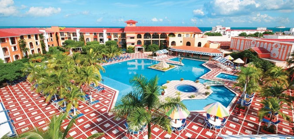 Vue a\u00e9rienne du Cozumel Hotel and Resort, avec sa grande piscine turquoise entour\u00e9e de palmiers.