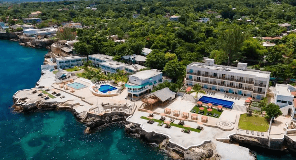 Vue a\u00e9rienne du Samsara Cliff Resort perch\u00e9 sur les falaises de Negril, avec ses piscines, ses terrasses am\u00e9nag\u00e9es et les eaux turquoise de la mer des Cara\u00efbes.