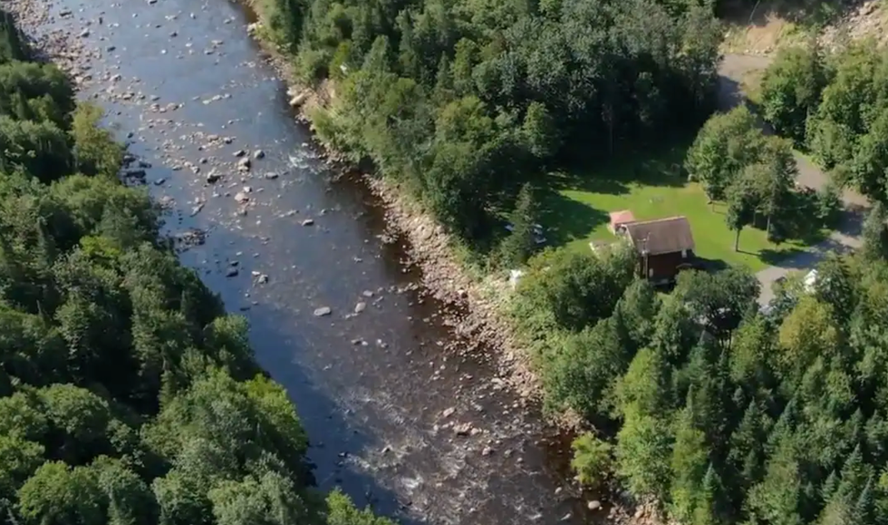 Vue a\u00e9rienne sur un chalet et la rivi\u00e8re adjacente.