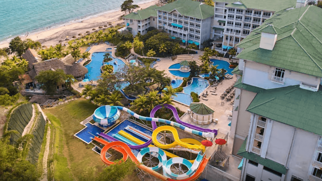 Vue aérienne du Gran Evenia Bijao montrant les piscines en cascade, les glissades d’eau colorées et la plage bordant le complexe.