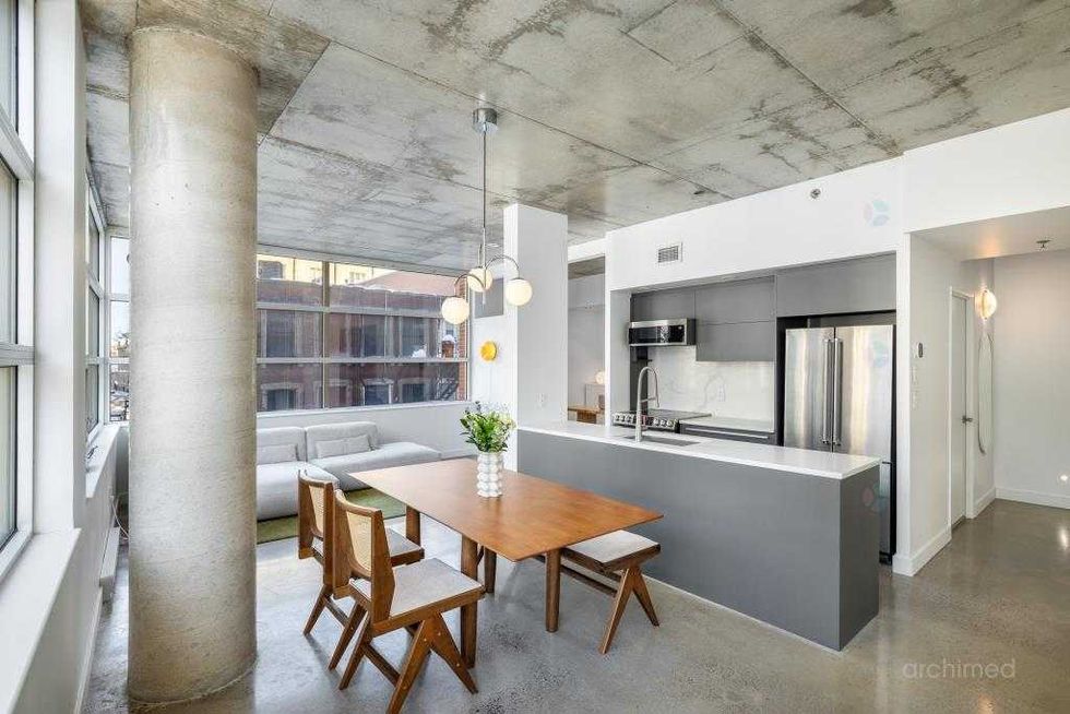 Vue d\u2019ensemble de l\u2019aire ouverte r\u00e9unissant cuisine, salle \u00e0 manger et salon dans un condo moderne et lumineux.