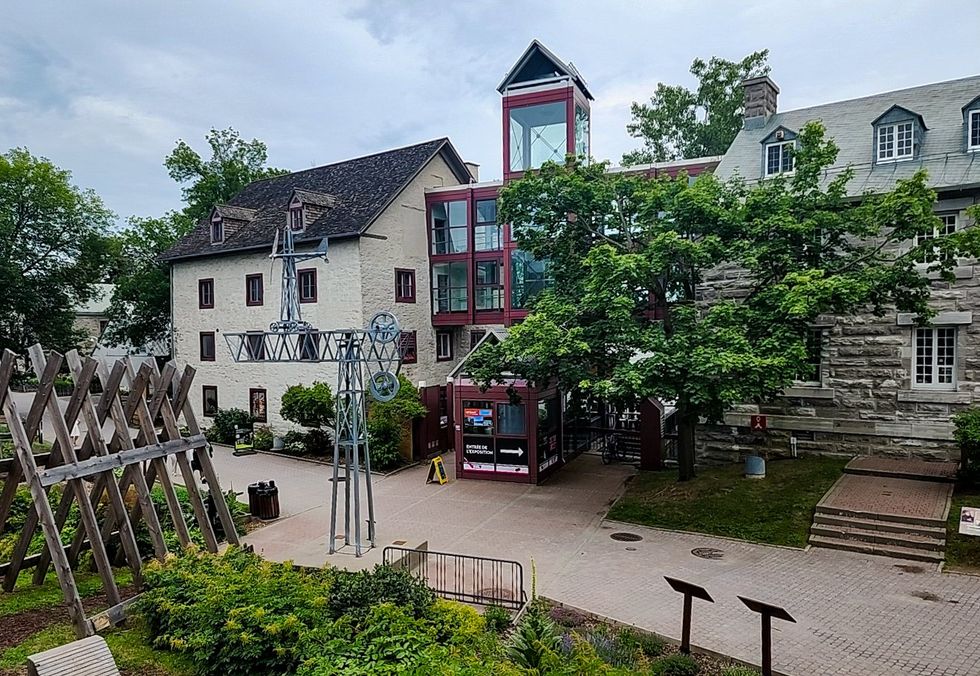 Vue de l'\u00cele-des-Moulins \u00e0 Terrebonne avec b\u00e2timents historiques et verdure.