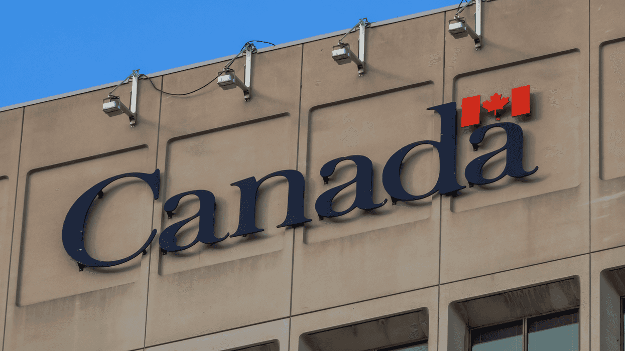 Vue en contre-plongée du logo officiel du Canada avec une feuille d'érable sur la façade en béton d'un immeuble fédéral.