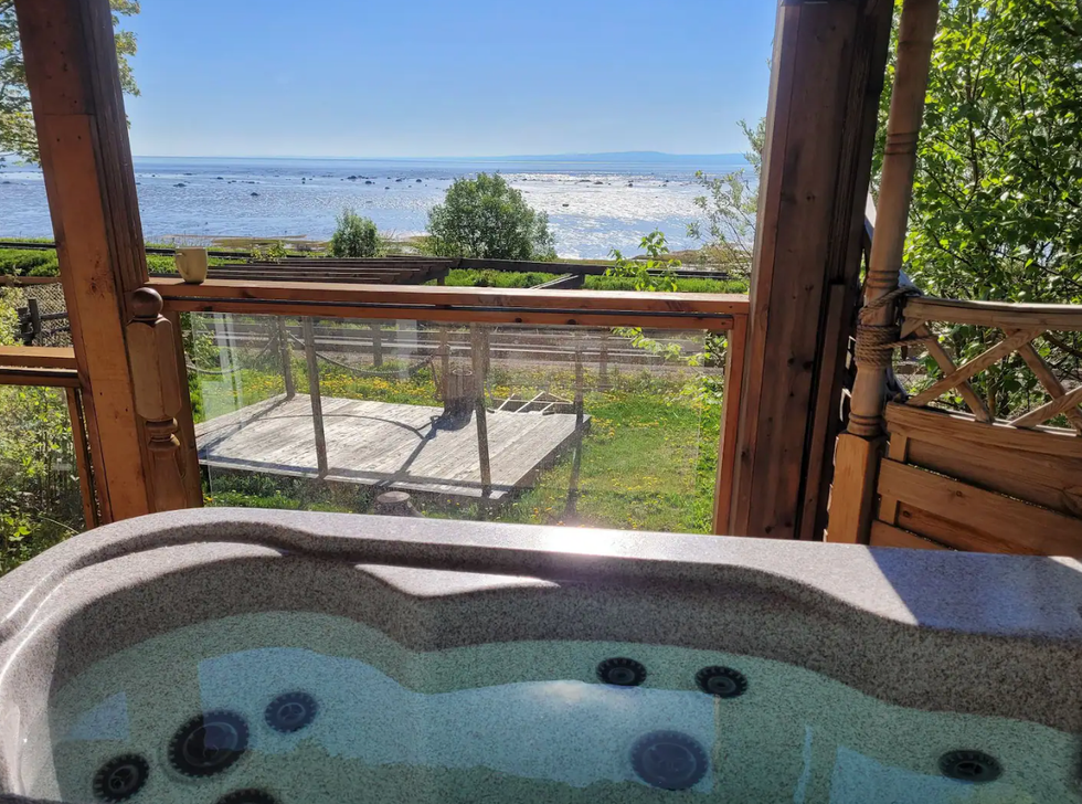 Vue \u00e0 partir du spa d'un chalet sur le terrain et le bord de l'eau.