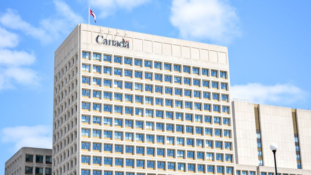 white government of canada building in ottawa with a canada sign and canadian flag