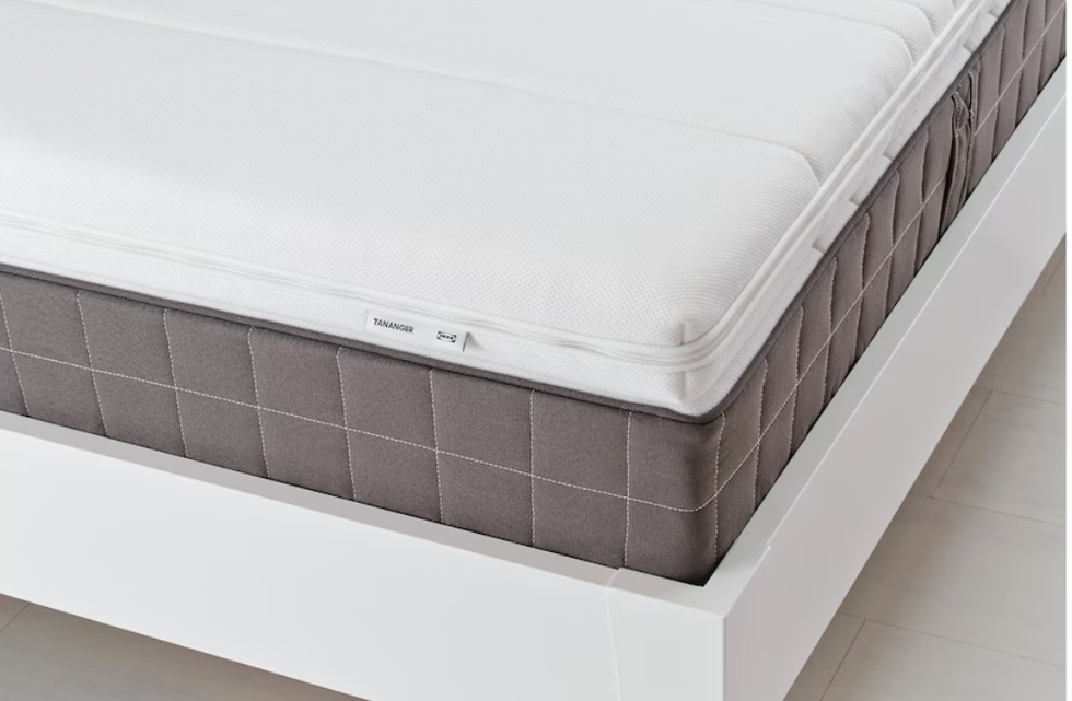 White mattress topper on top of a mattress and white bed frame.