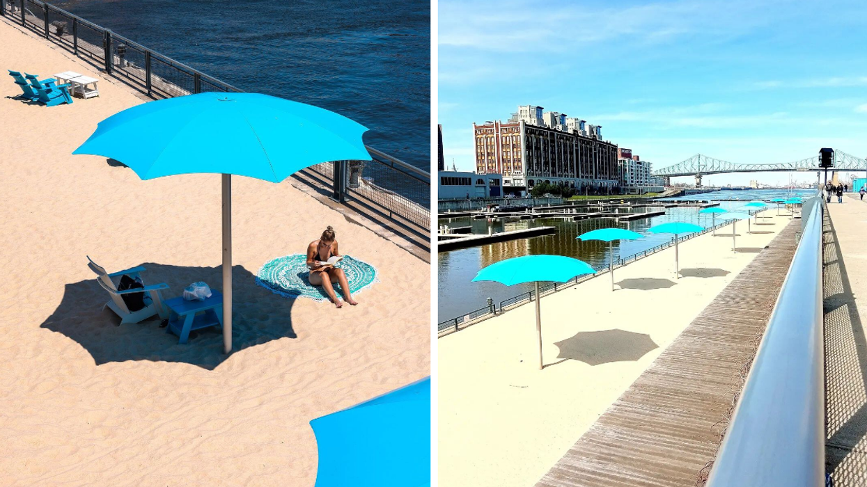White sand beach stretch with blue umbrellas next to a river and downtown city.