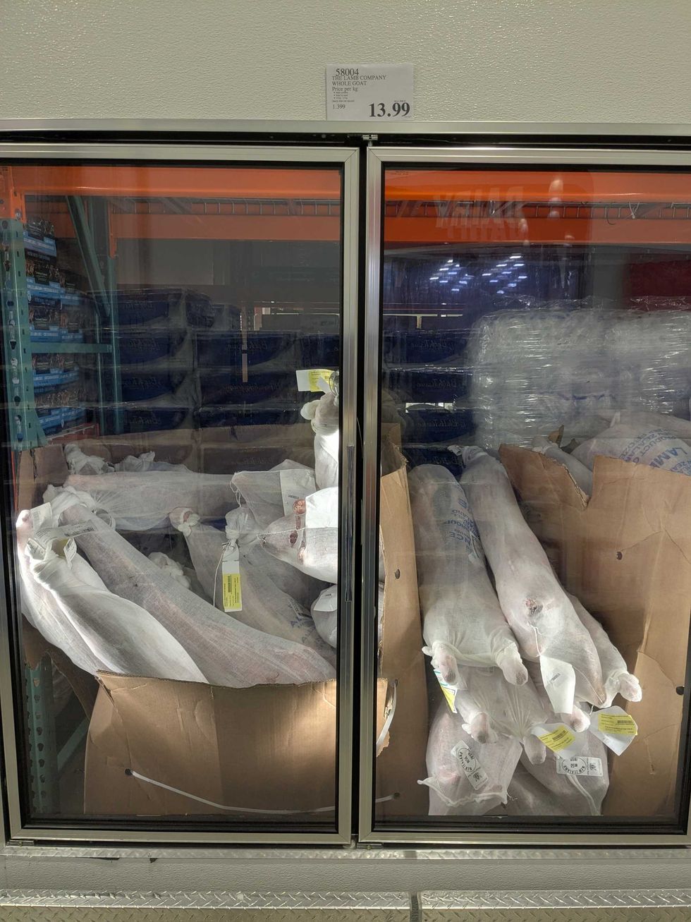 Whole goats in mesh bags displayed in a freezer