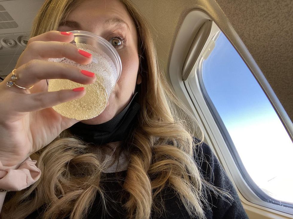 woman drinking prosecco on board a Swoop flight from Toronto to Cancun