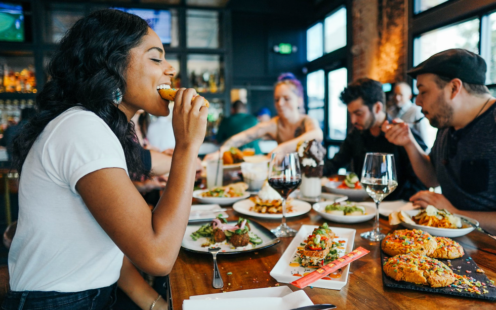 woman eating bread at a table with a group of people and wine