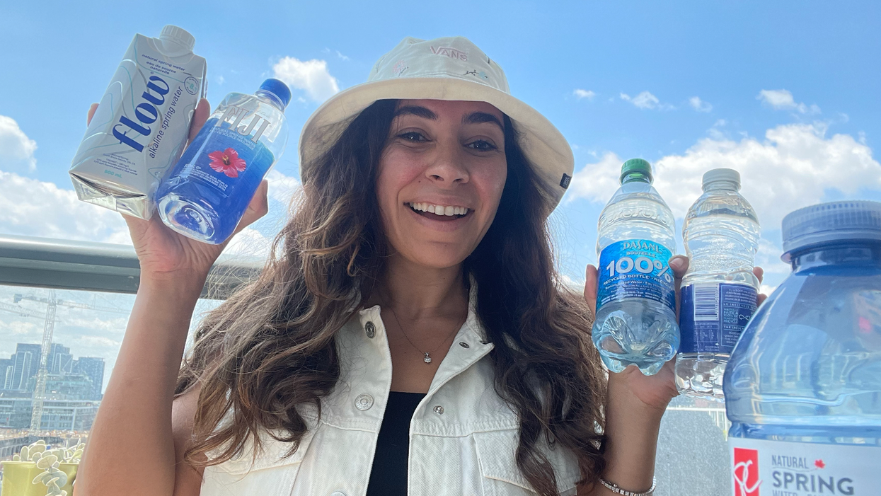 woman holding five bottles of water on a balcony with a clear blue sky