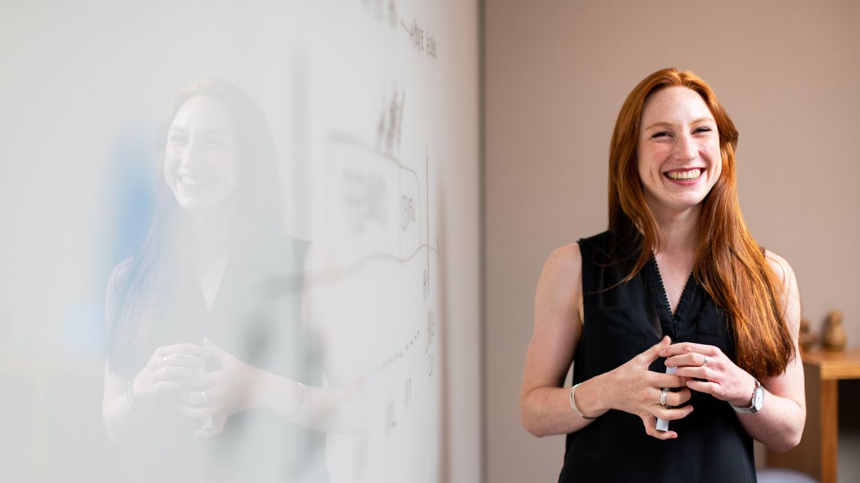 Woman smiling next to a whiteboard.