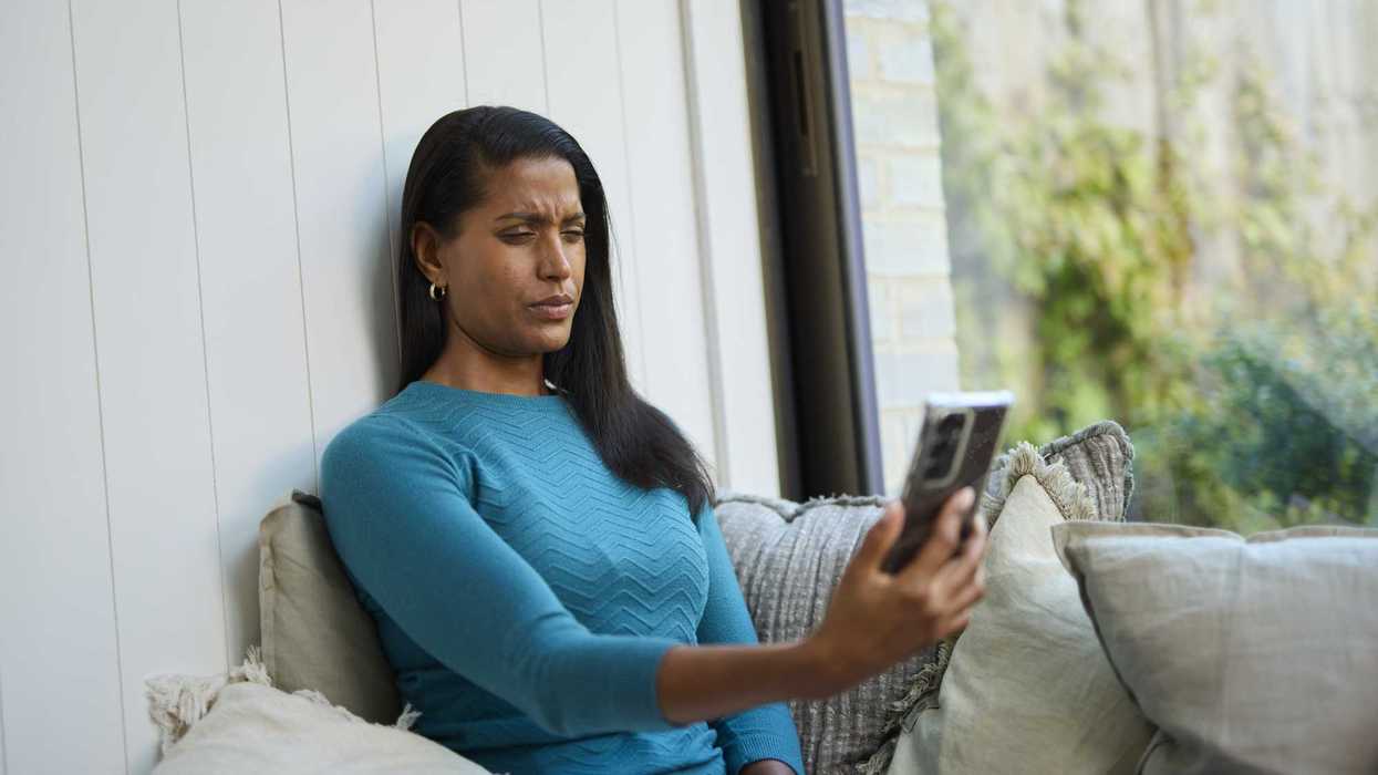 Woman squinting at her phone on a couch.