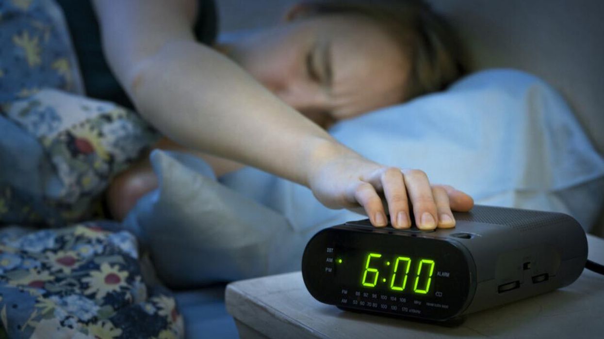 Woman waking up to alarm clock going off.