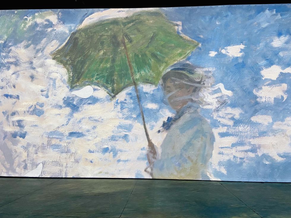 "Woman with a Parasol" painting by Claude Monet projected on a wall.