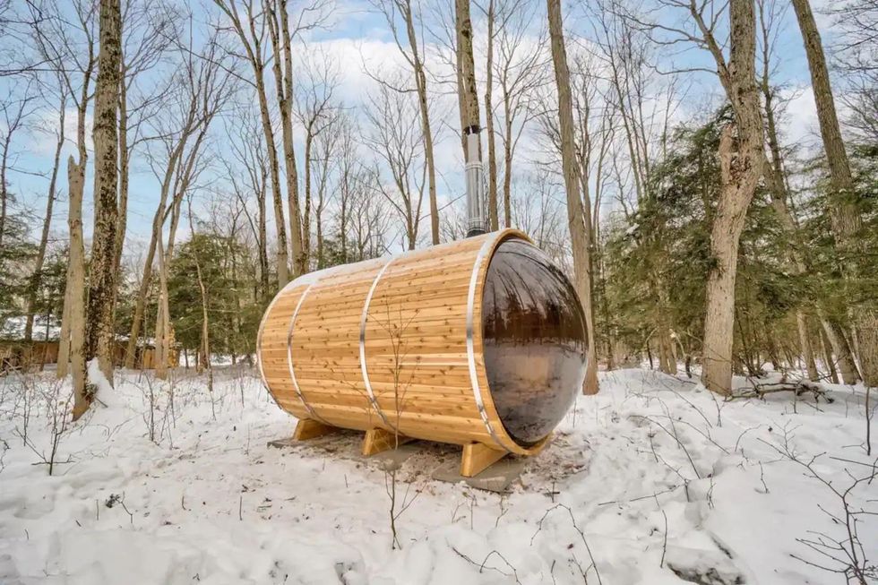 Wood-burning barrel sauna in a snowy forest.