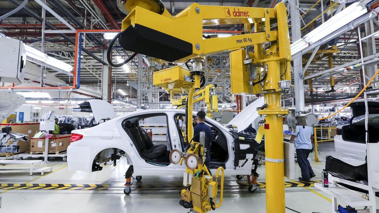 Workers assembling cars at an automobile assembly line production plant.